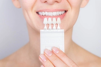 Patient holding veneer shade samples to check colour against their teeth